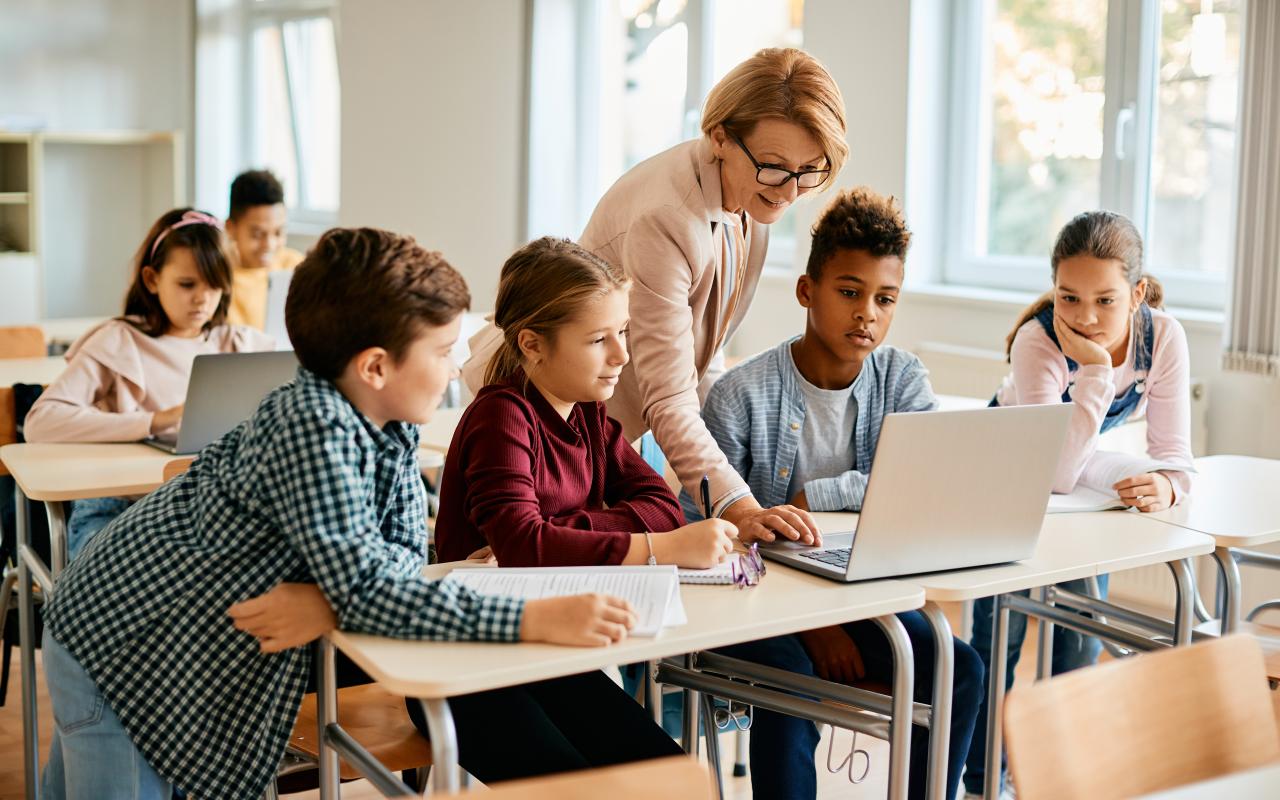 Kinderen krijgen uitleg van leraar in klaslokaal met laptop