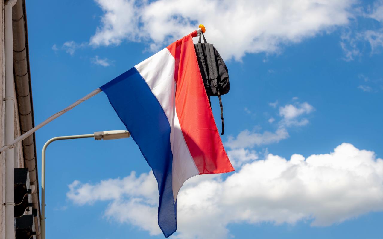 De Nederlandse vlag met een rugzak hangt uit